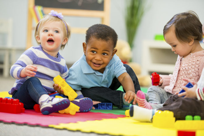 A group of children sitting on the floor playing with toys.