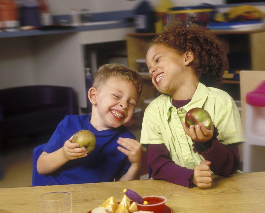 Two children eating apples at a table.