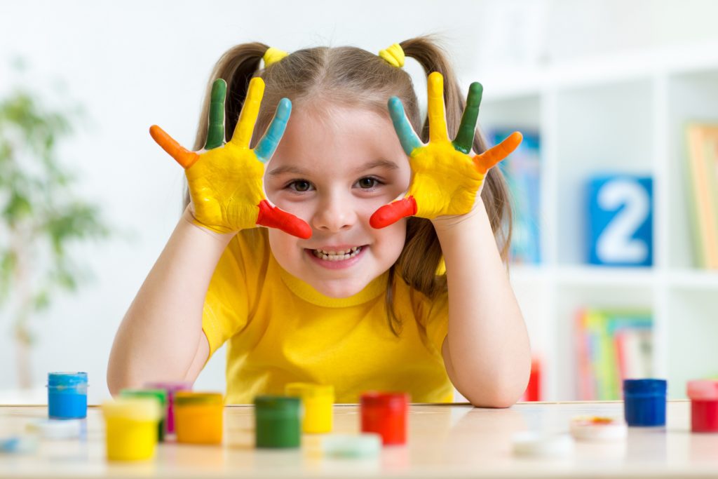 A little girl with paint on her hands.